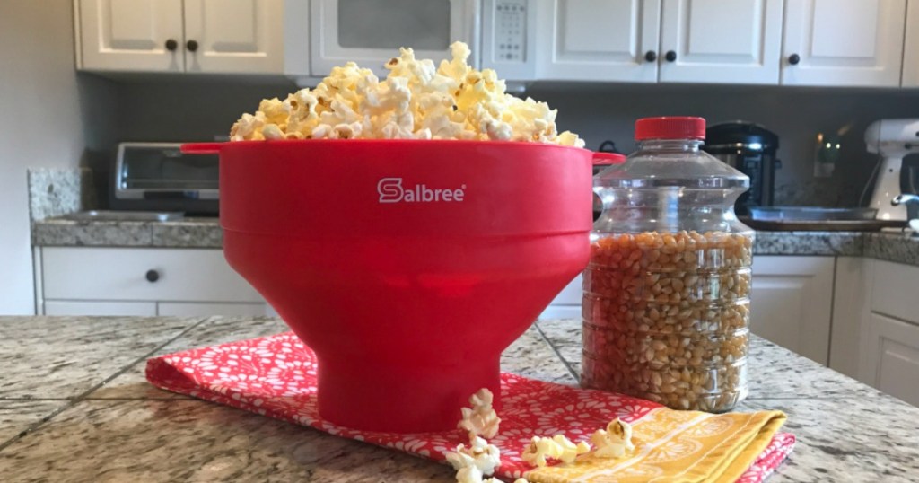 red Salbree popcorn popper with jar of popcorn kernels next to it