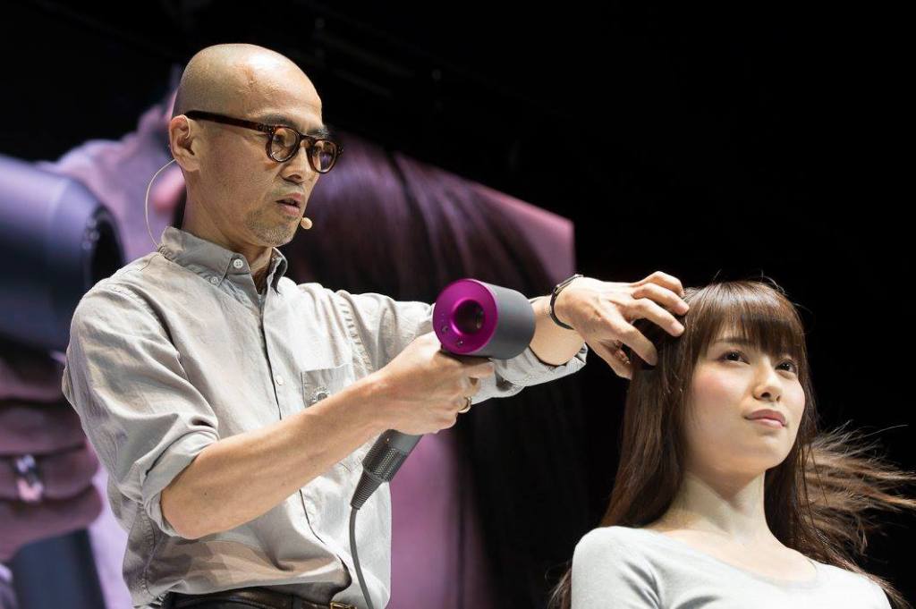 man drying woman's hair with Dyson hair dryer