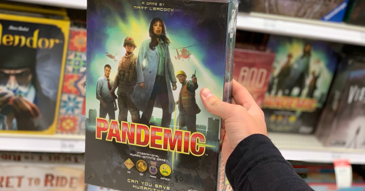 hand holding pandemic board game in store in front of other games