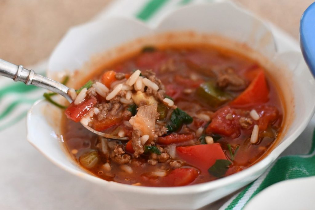 spooning stuffed pepper soup from red bowl