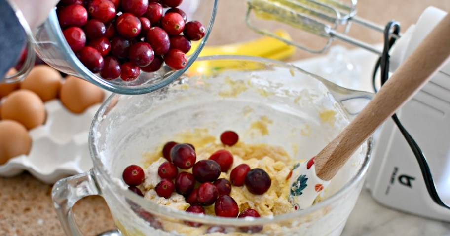 pouring in cranberries to christmas cake batter