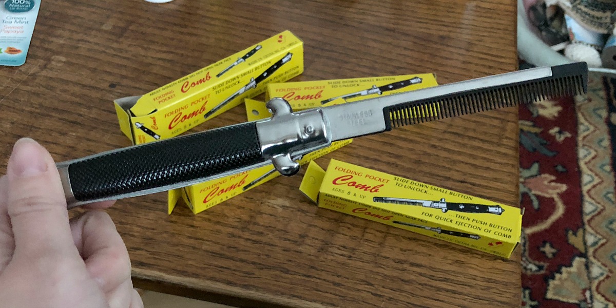 hand holding switchblade comb above table with yellow boxes