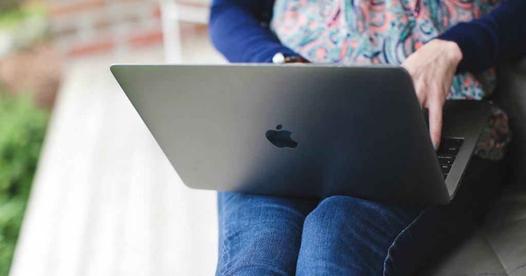 woman holding and typing on an apple macbook