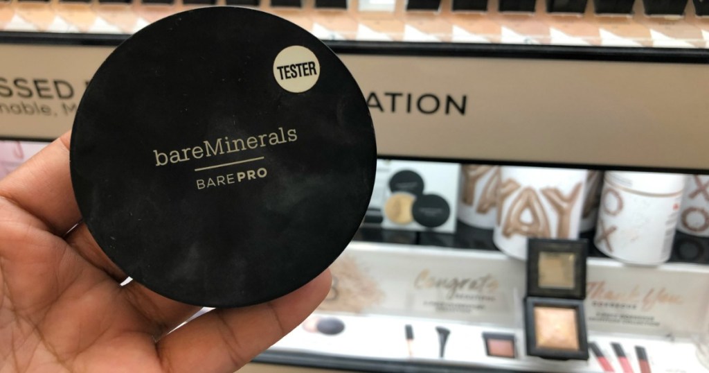 hand holding bare minerals powder foundation in store aisle