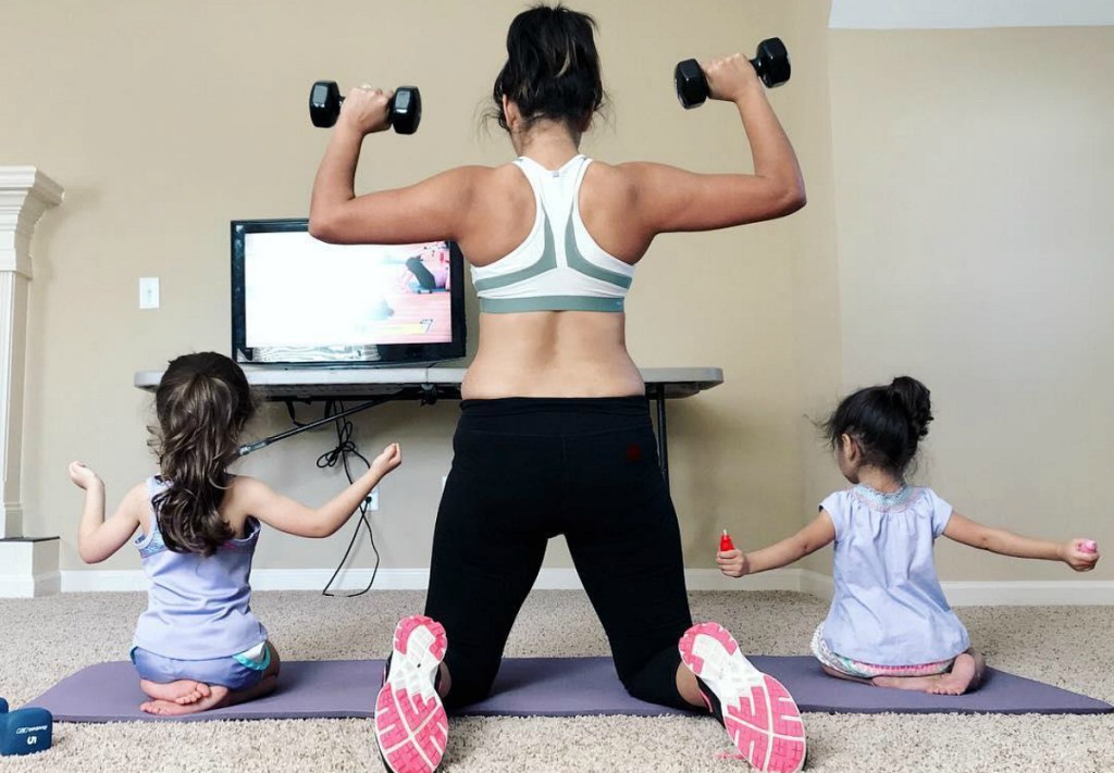 woman lifting weights with kids on either side 