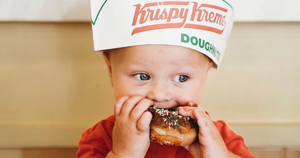 little boy biting into a donut with a hat on