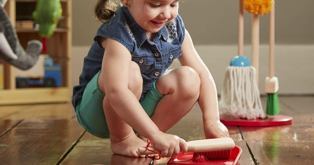 young girl using a cleaning playset to sweep