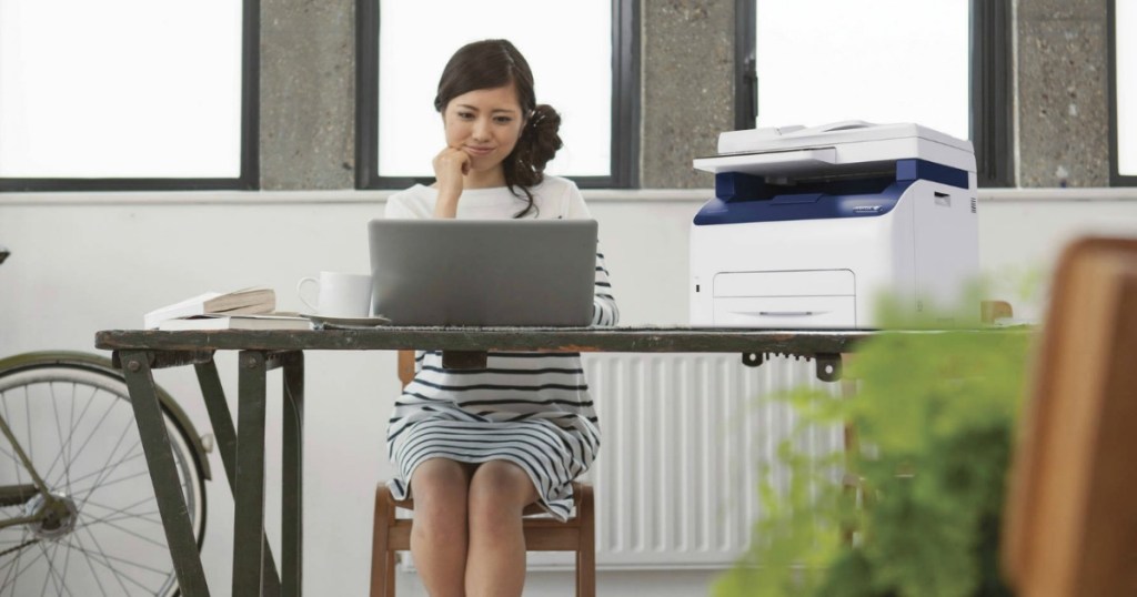 Woman at desk on laptop next to copy machine