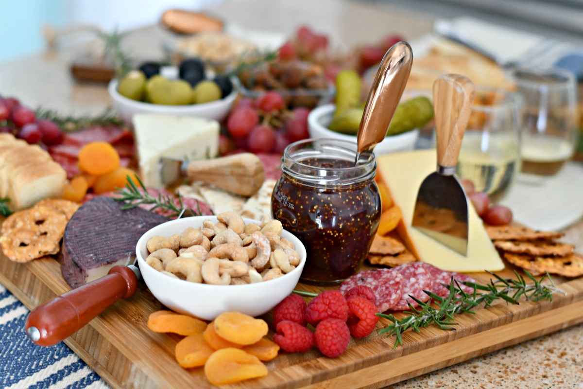 nuts, dried fruit, jam, cheese, olives on cutting board