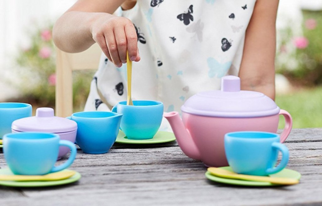 girl playing with green toys tea set