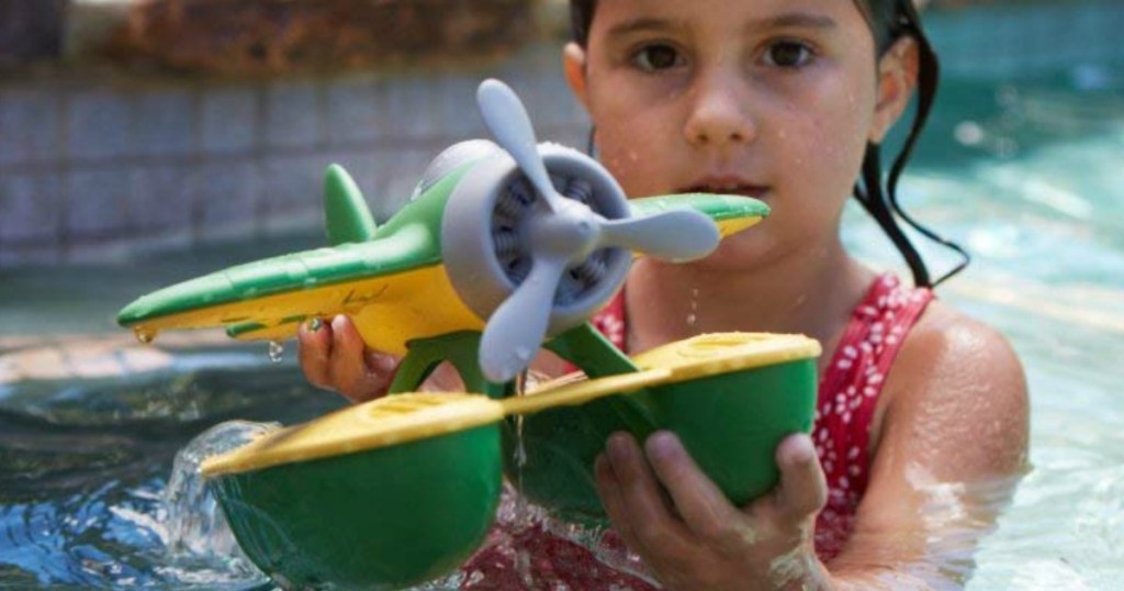 little girl playing with a green toys plane in pool
