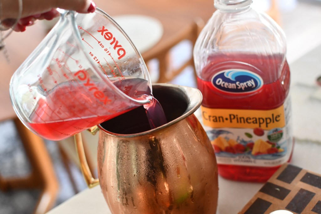 pouring cranberry juice into a copper pitcher