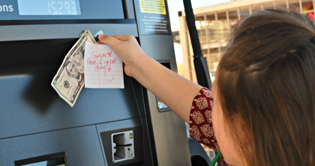 girl taping money to a gas tank