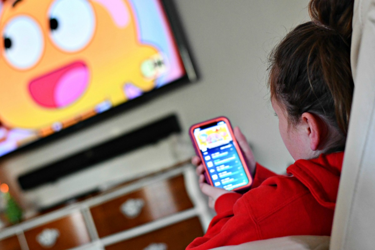 I saved 1200 on cable by streaming – child looking at a mobile device while watching tv