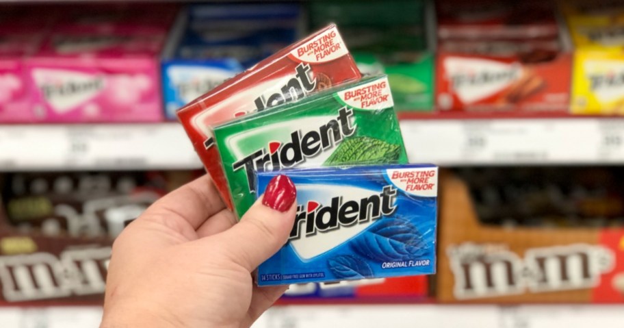 Hand holding three packs of trident gum