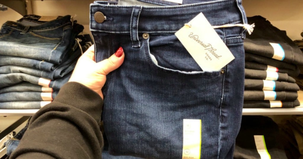 woman holding up a pair of Universal Thread jeans in a store