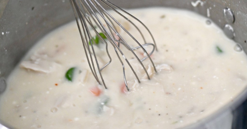 whisking creamy chicken noodle soup on stove