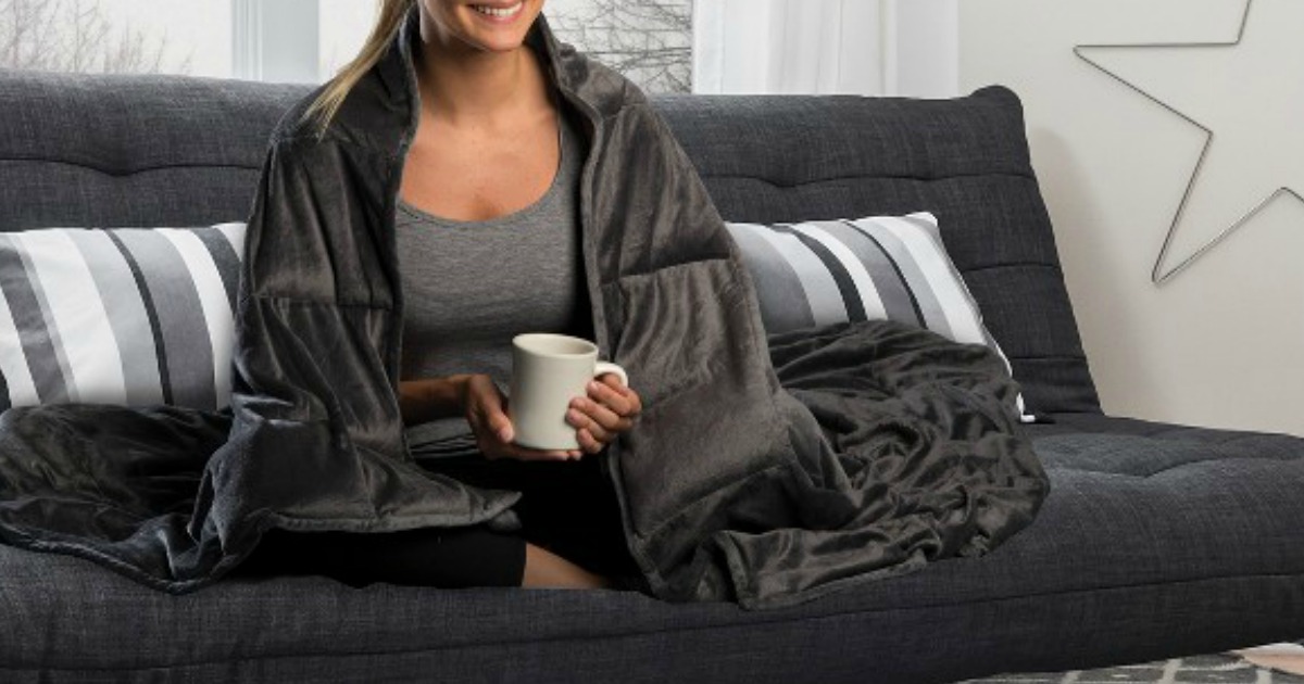 woman wrapped in blanket sitting on a couch holding a mug