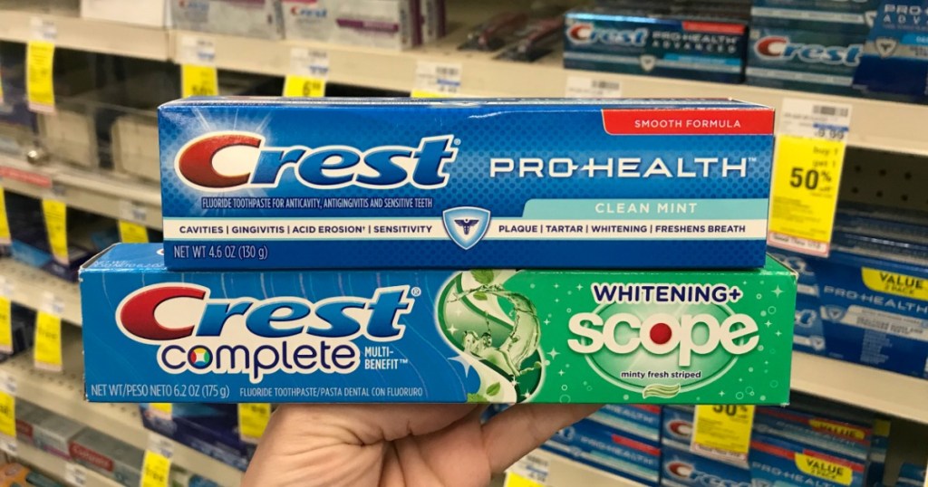 Hand holding Crest Complete and Pro-Health Toothpaste