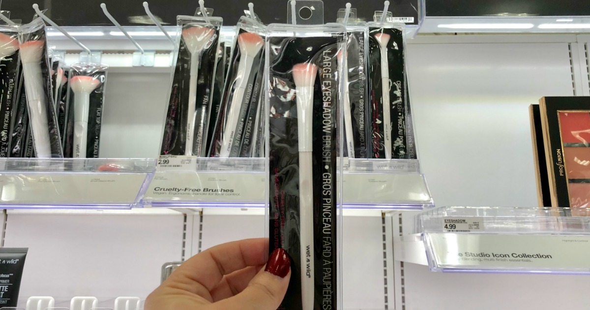 hand holding up a makeup brush in front of a store display