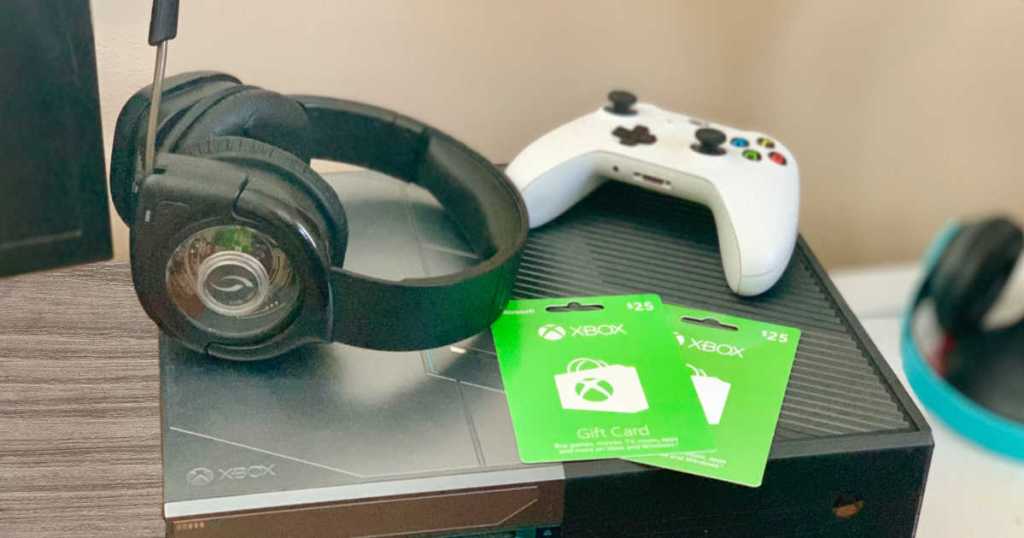 xbox console with white wireless controller, wireless headset and two $25 xbox gift cards on top