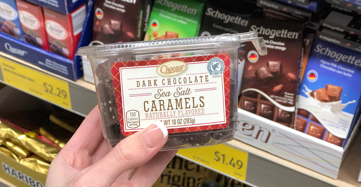 hand holding a clear container of dark chocolate sea salt caramels