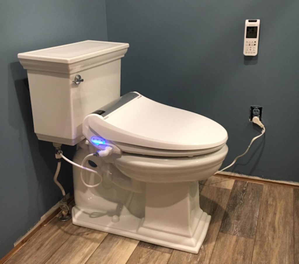 white toilet with blue neon light under seat in bathroom with dark blue gray walls
