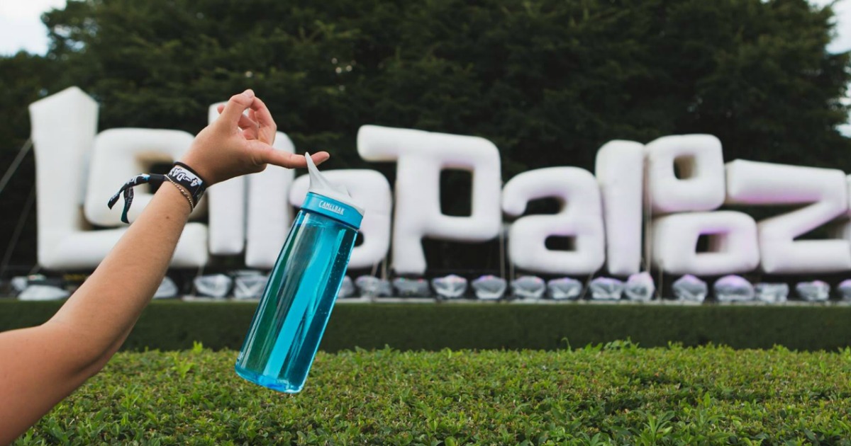 hand holding camelbak water bottle in front of lollapalooza sign