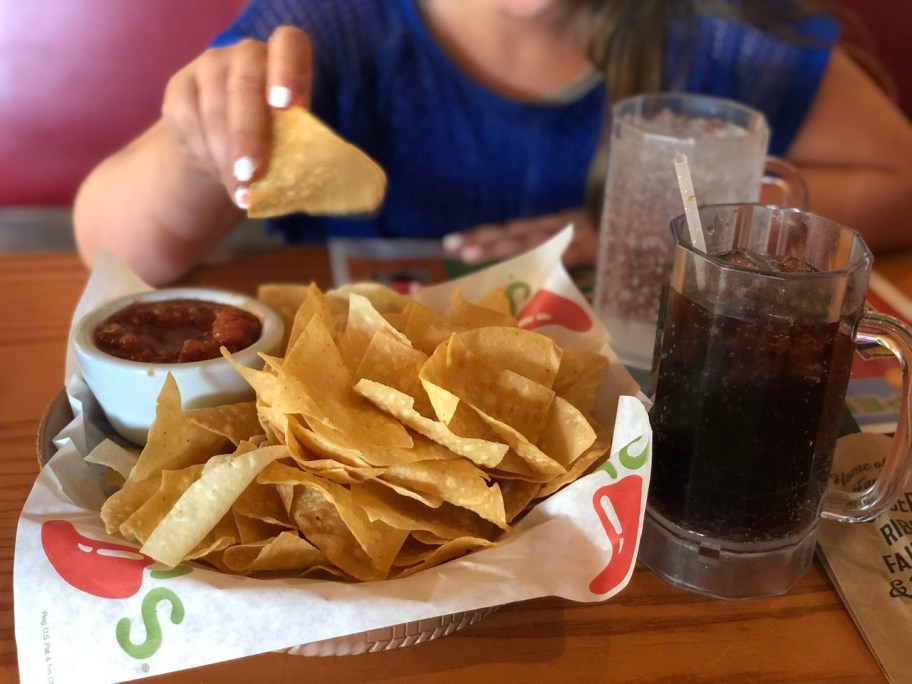 person dipping chip into salsa at chilis table