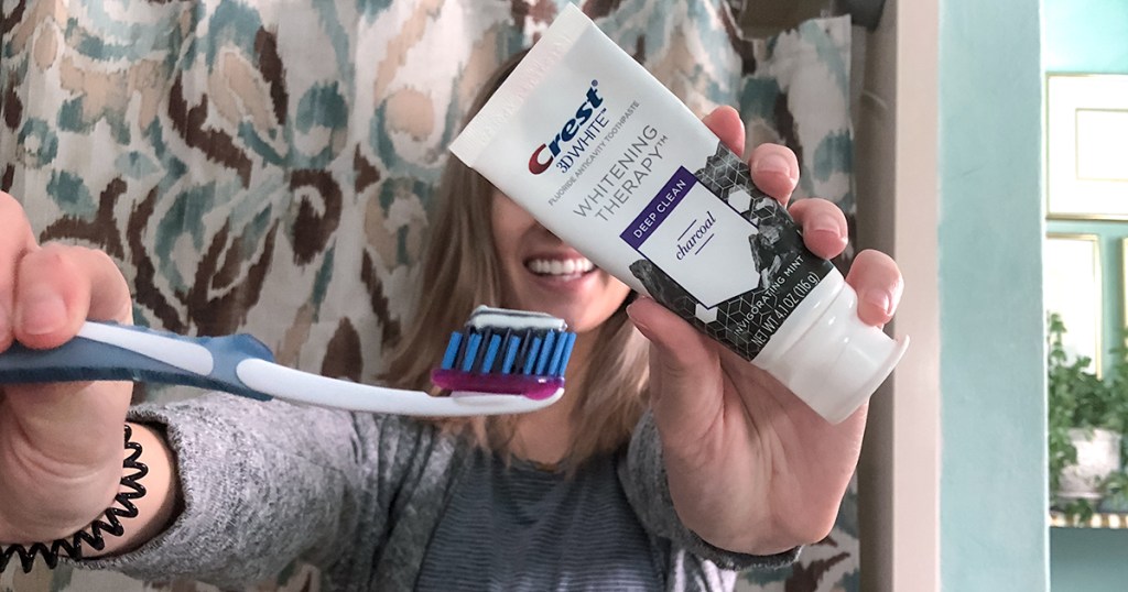 holding up toothbrush and crest whitening therapy toothpaste