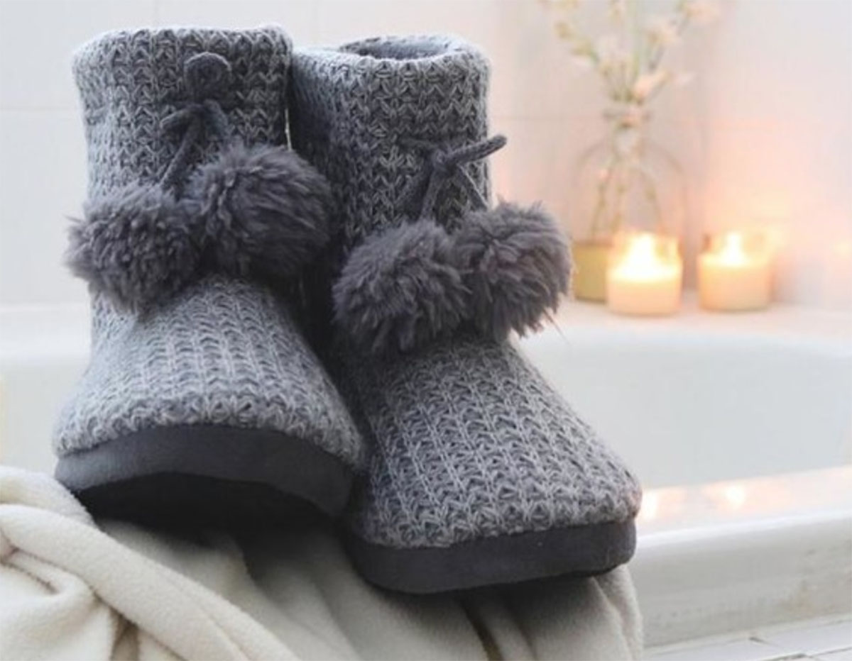 grey Isotoner slippers on a fuzzy blanket