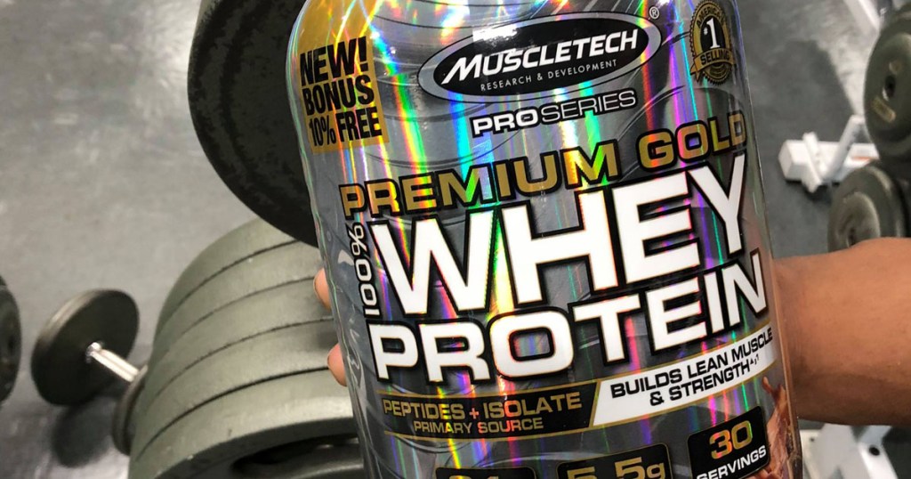 Large canister of protein powder in gym near workout gear