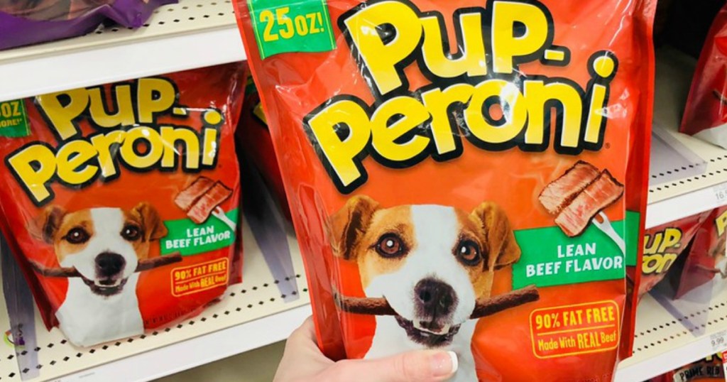 woman's hand holding a 25 oz bag of Pup-peroni dog snacks