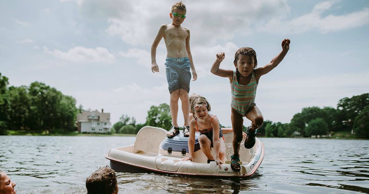 Kids in swimming suits jumping off a paddle boat