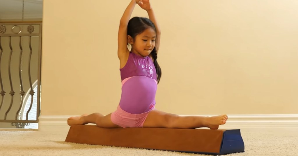 girl doing the splits on a balance beam