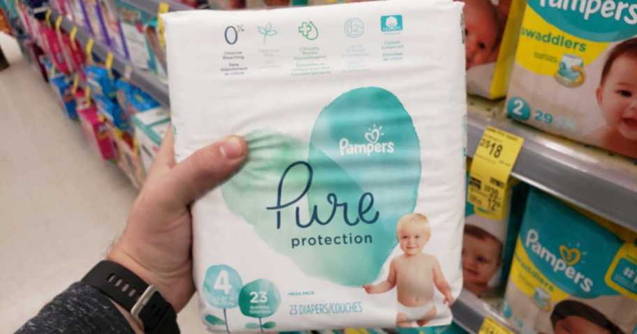 A hand holding Pampers Pure Protection Diapers