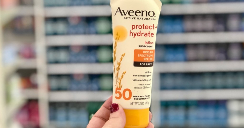 hand holding bottle of Aveeno sunscreen