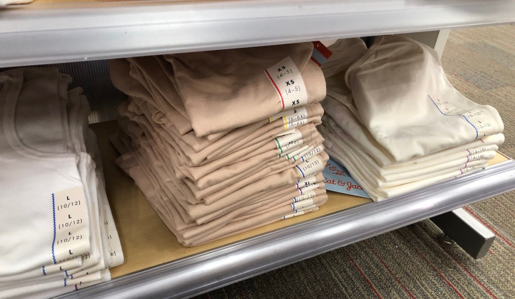neutral colored camis folded in a pile on a shelf