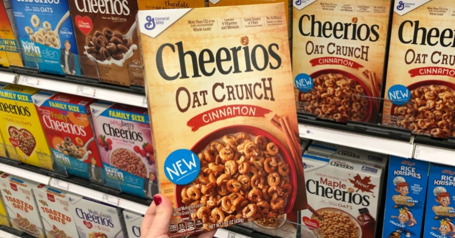 holding a box of cheerios oat crunch cinnamon