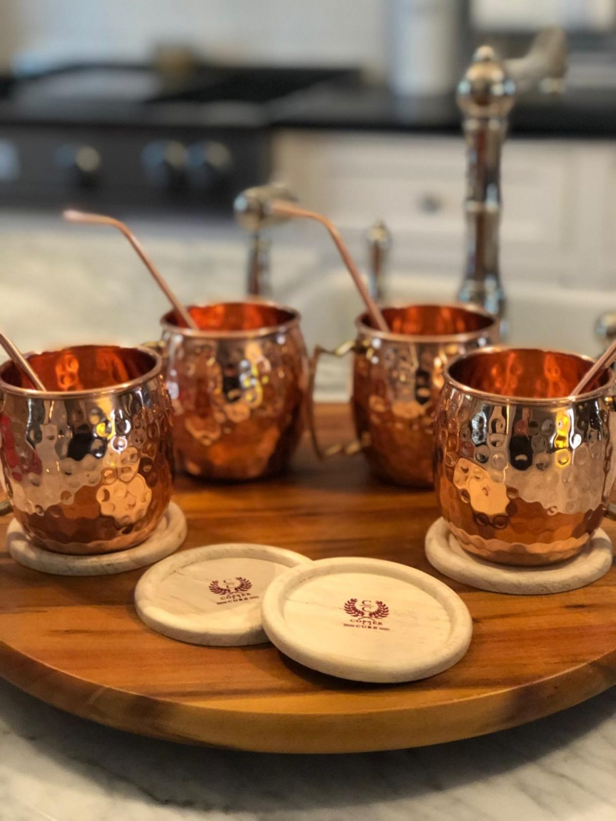 copper mugs with straws on wood tray