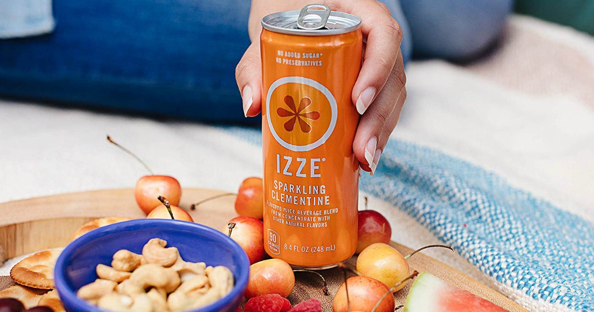 hand holding an orange can of IZZE sparkling fruit juice on a tray with food