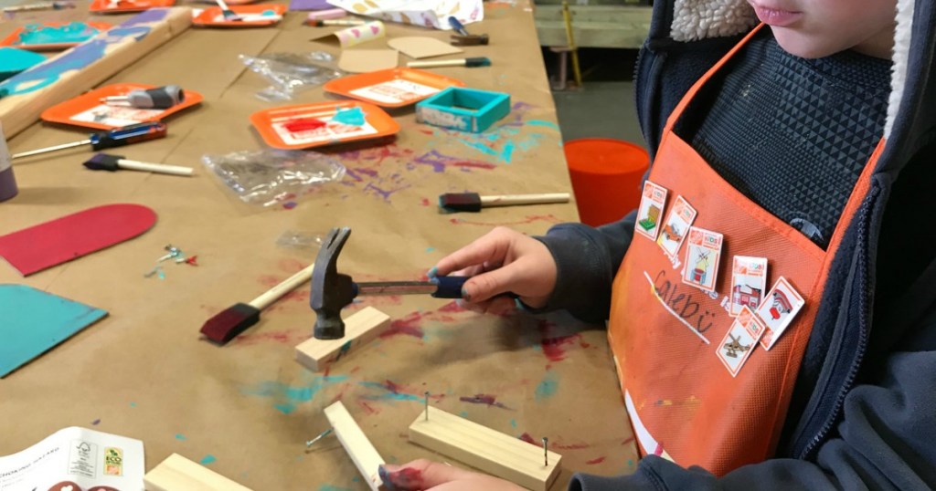 child holding hammer building with wood, nails, paint and brushes