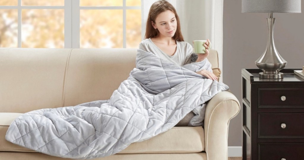 woman sitting on couch with weighted blanket over her