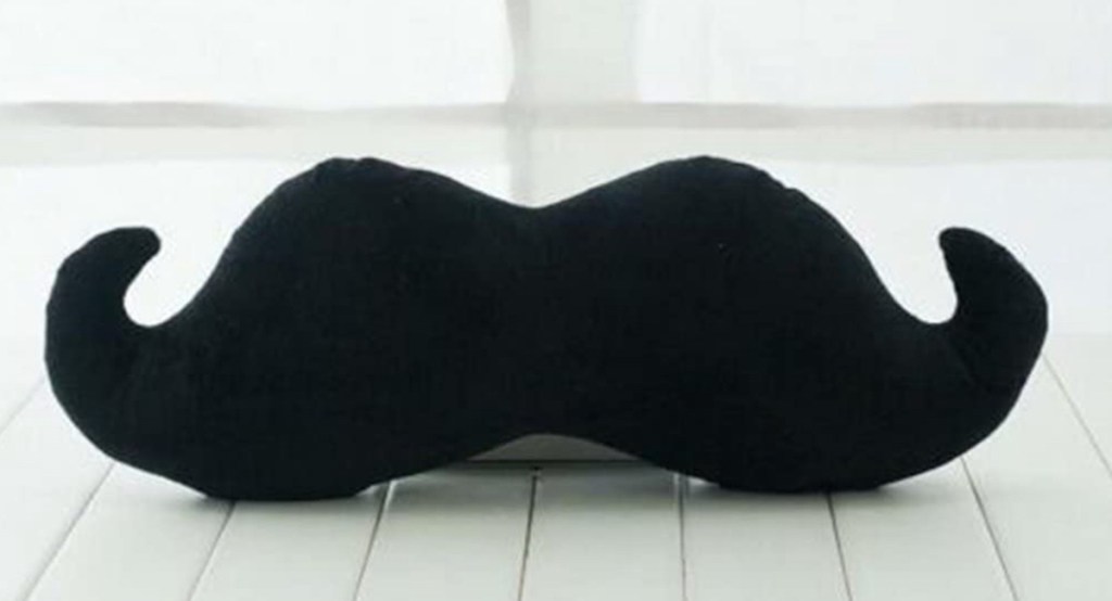 black mustache kids throw pillow sitting on wood floor