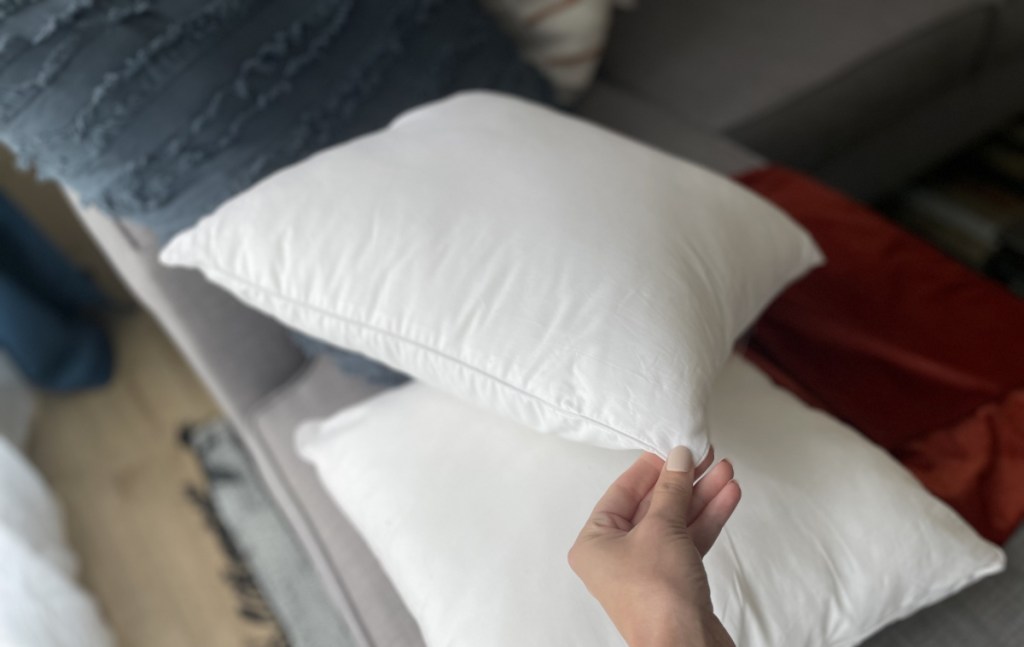 hand holding pillow insert outside of throw pillow case