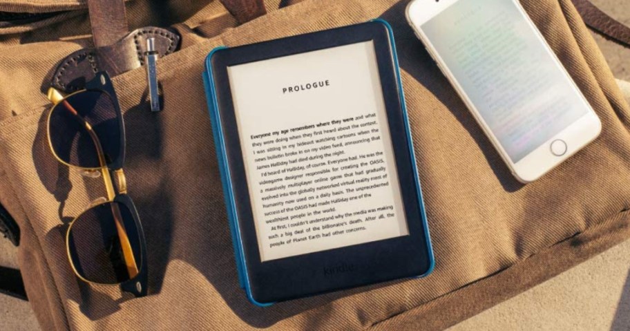 kindle on a bag next to sunglasses