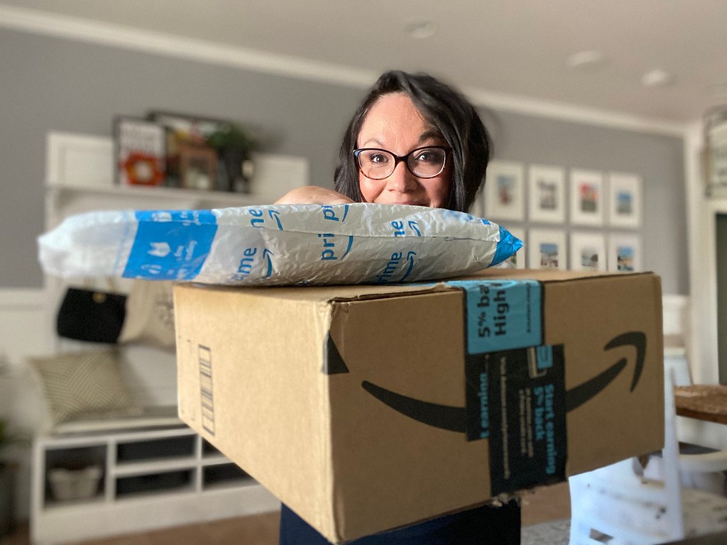 woman holding up Amazon Prime package and box