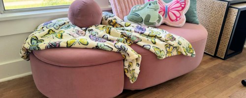 Pink chaise and ottoman with colorful blankets on top