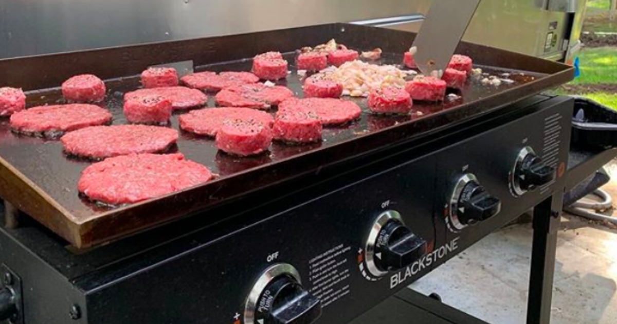 hamburgers and diced onions being cooked outside on a Blackstone griddle