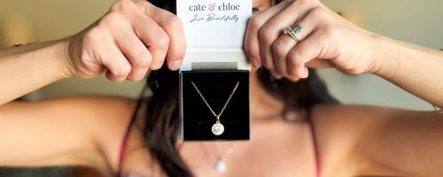 Woman holding cate and Chloe necklace